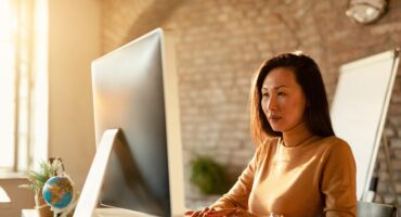 woman in office typing and looking at big monitor