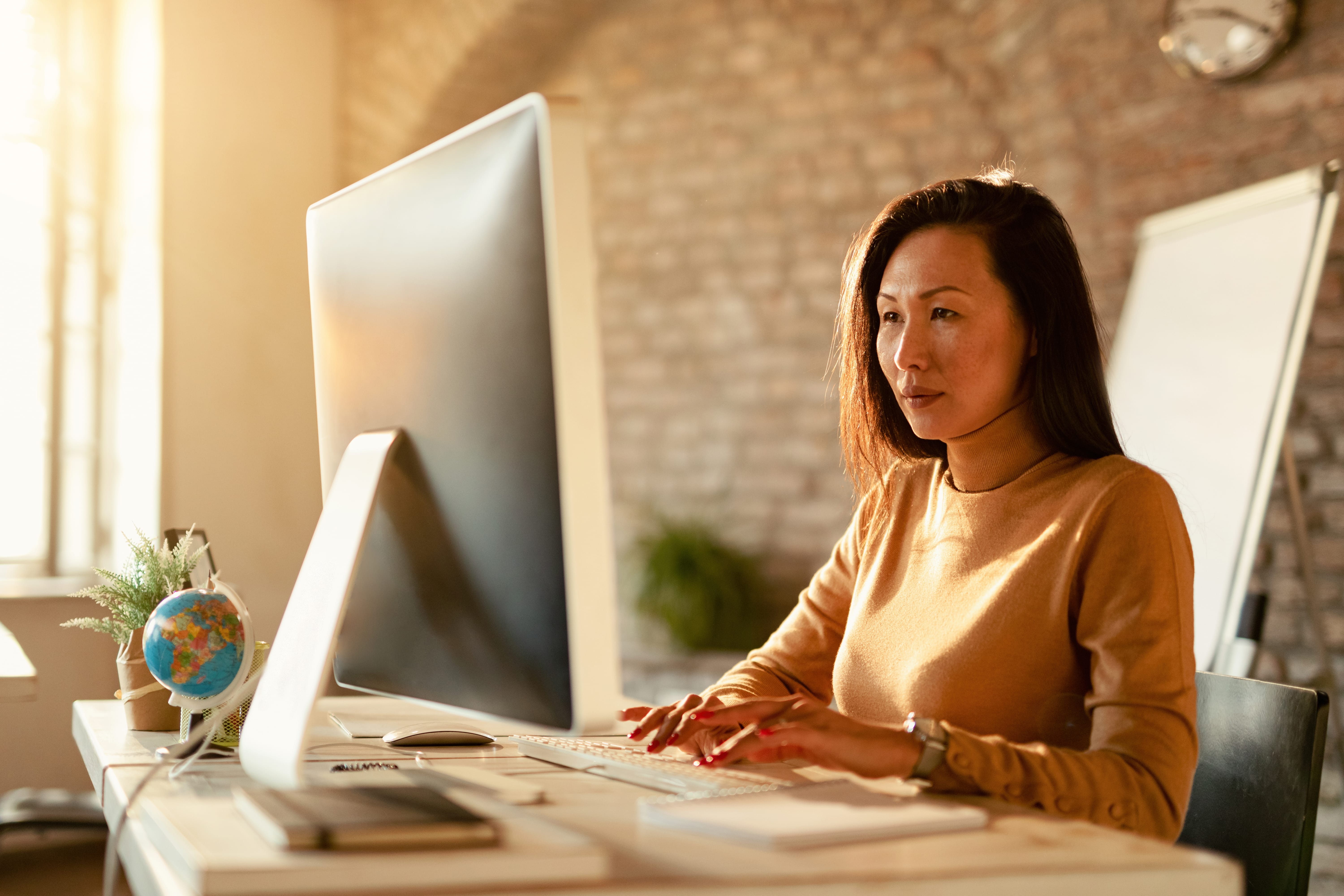 woman in office typing and looking at big monitor